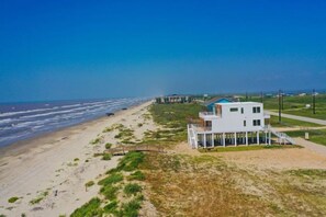 Una casa moderna frente a la playa con balcón, ubicada en una playa arenosa y vistas al océano.