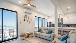 A modern living room with a large sofa, a coffee table, and a view of the ocean.