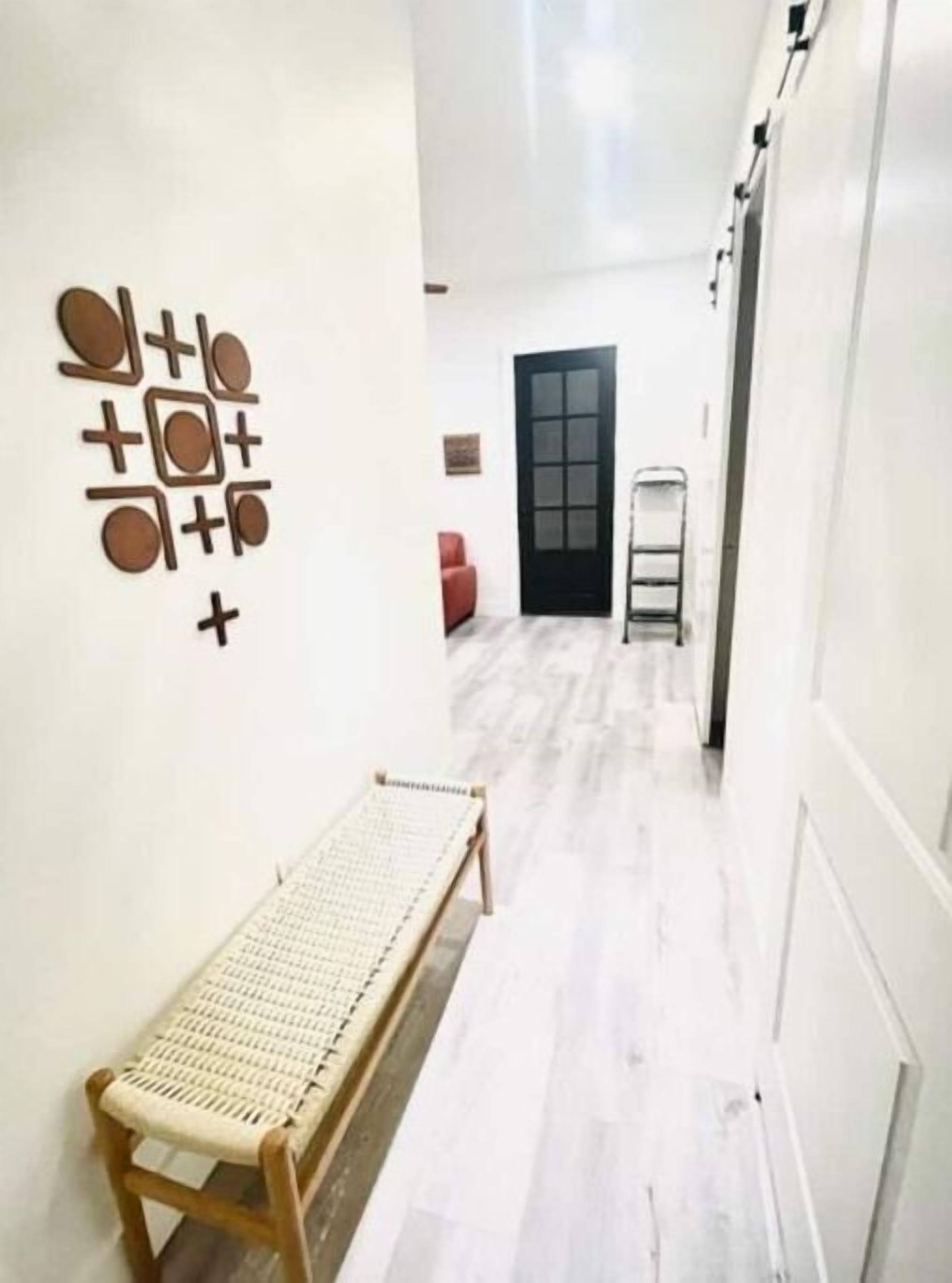 A narrow hallway with a bench, a door, and a wall-mounted decoration.