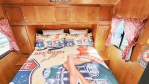 Interior compacto de madeira com uma cama e roupa de cama com tema vintage da Rota 66.