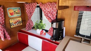 Uma cozinha compacta com cafeteira, uma pequena planta e uma garrafa de Coca-Cola.