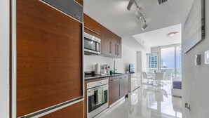 A modern kitchen with stainless steel appliances, wooden cabinets, and a large window offering a city view. - Icon Tower 3 (Miami)