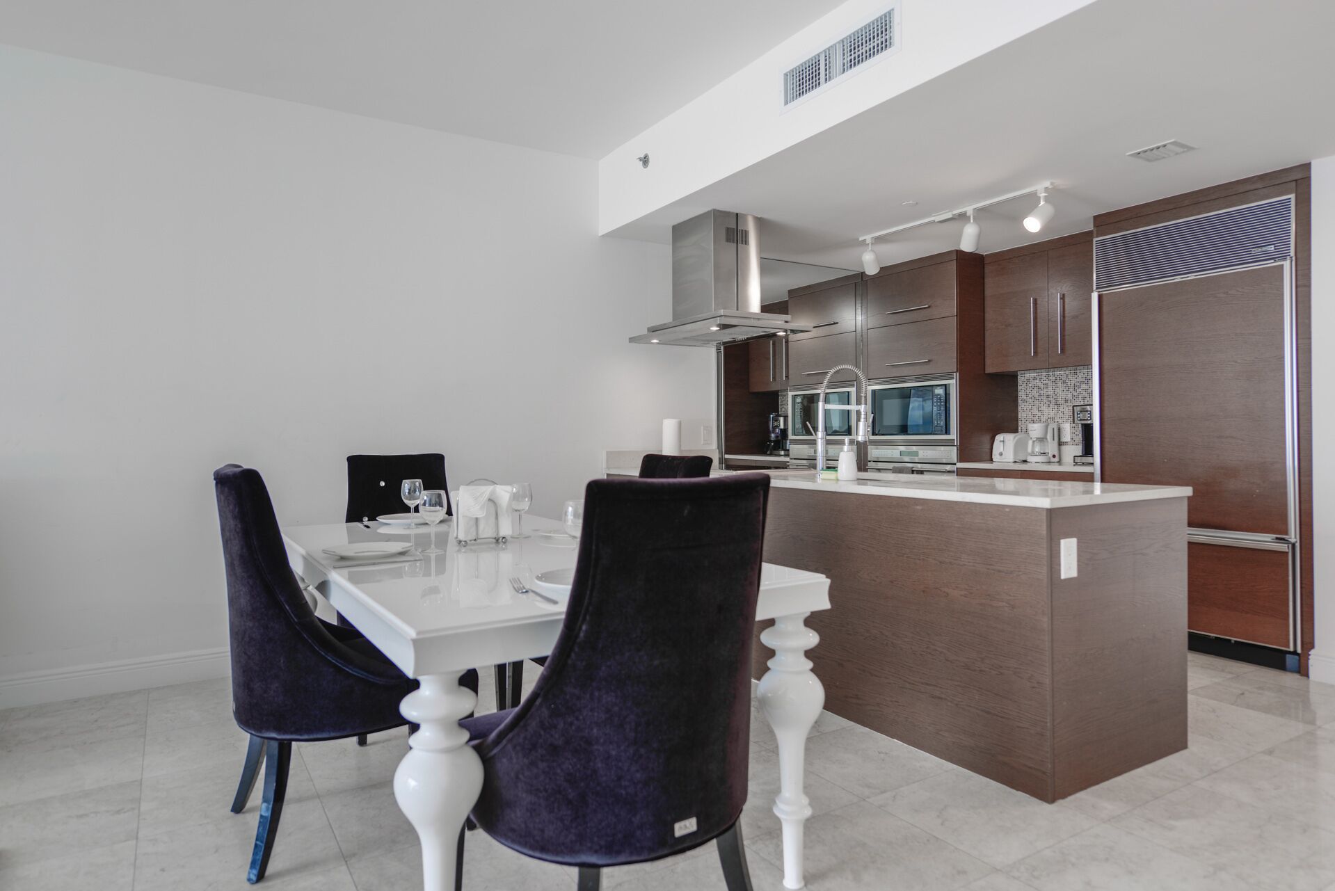 A modern kitchen with a central island, stainless steel appliances, and dark wooden cabinets.