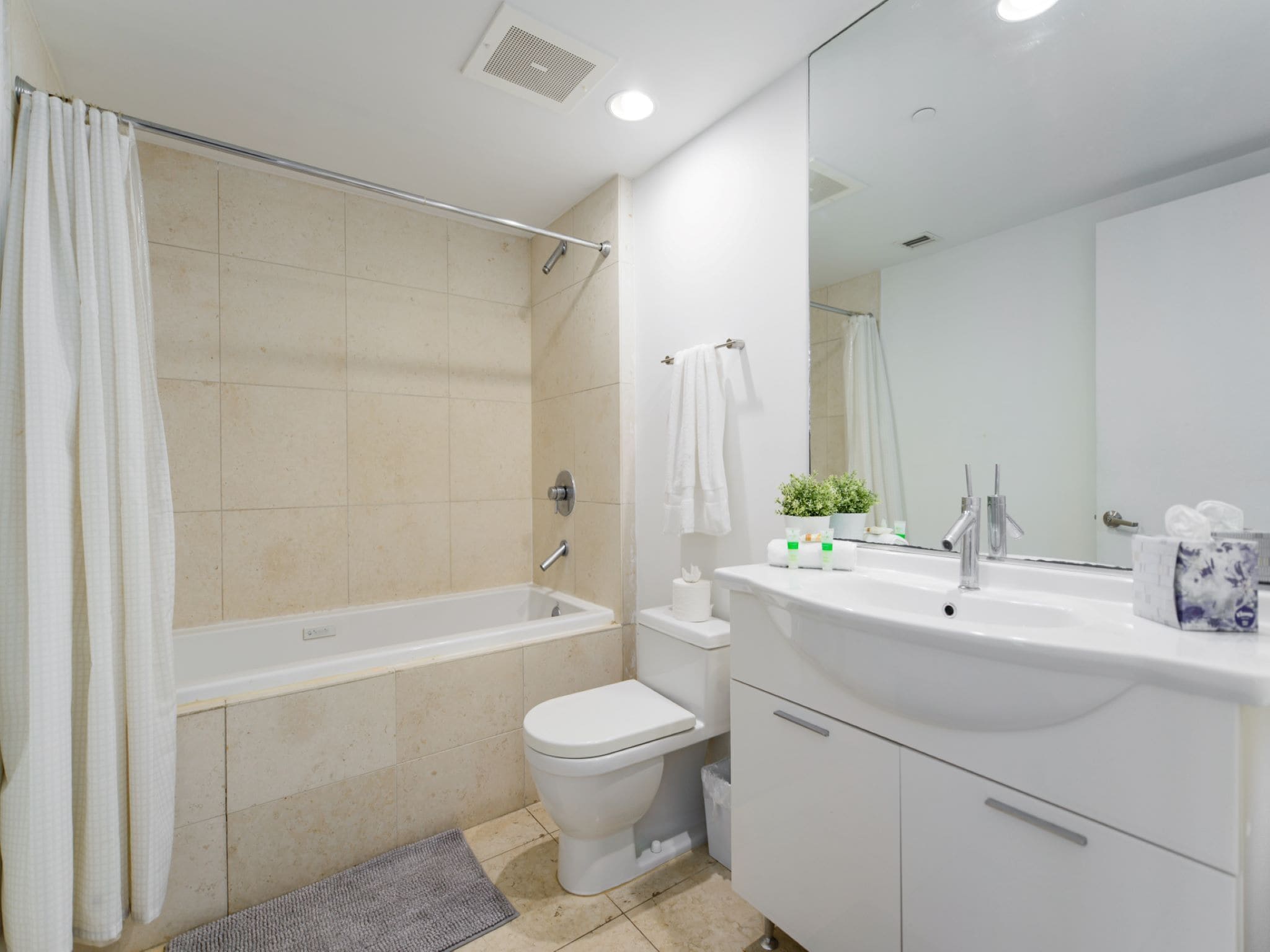 A modern bathroom with a bathtub, toilet, sink, and mirror.