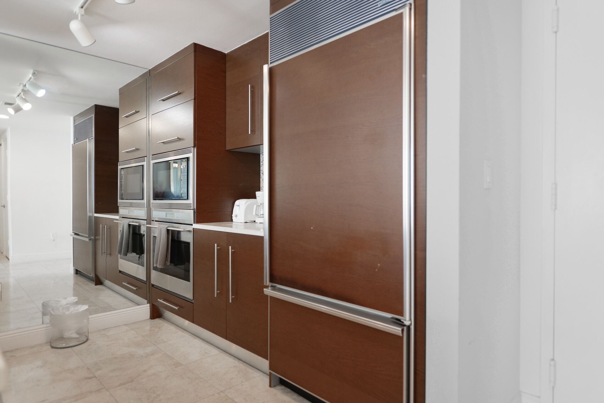 A modern kitchen with stainless steel appliances, wooden cabinets, and a white countertop.