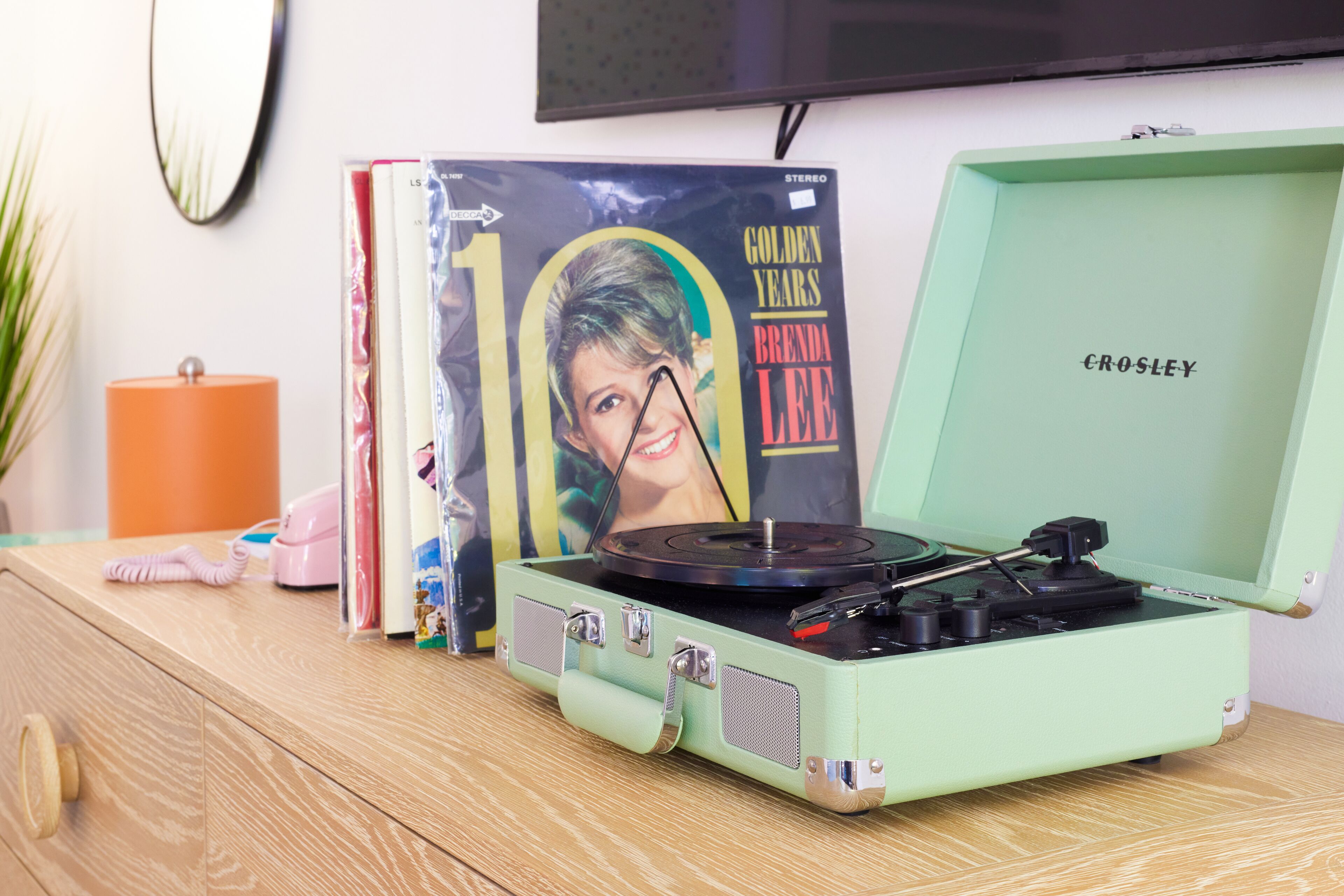 Un vieux tourne-disque vert, avec une pochette de disque portant l’inscription « Golden Years Brenda Lee », posé sur une surface en bois.