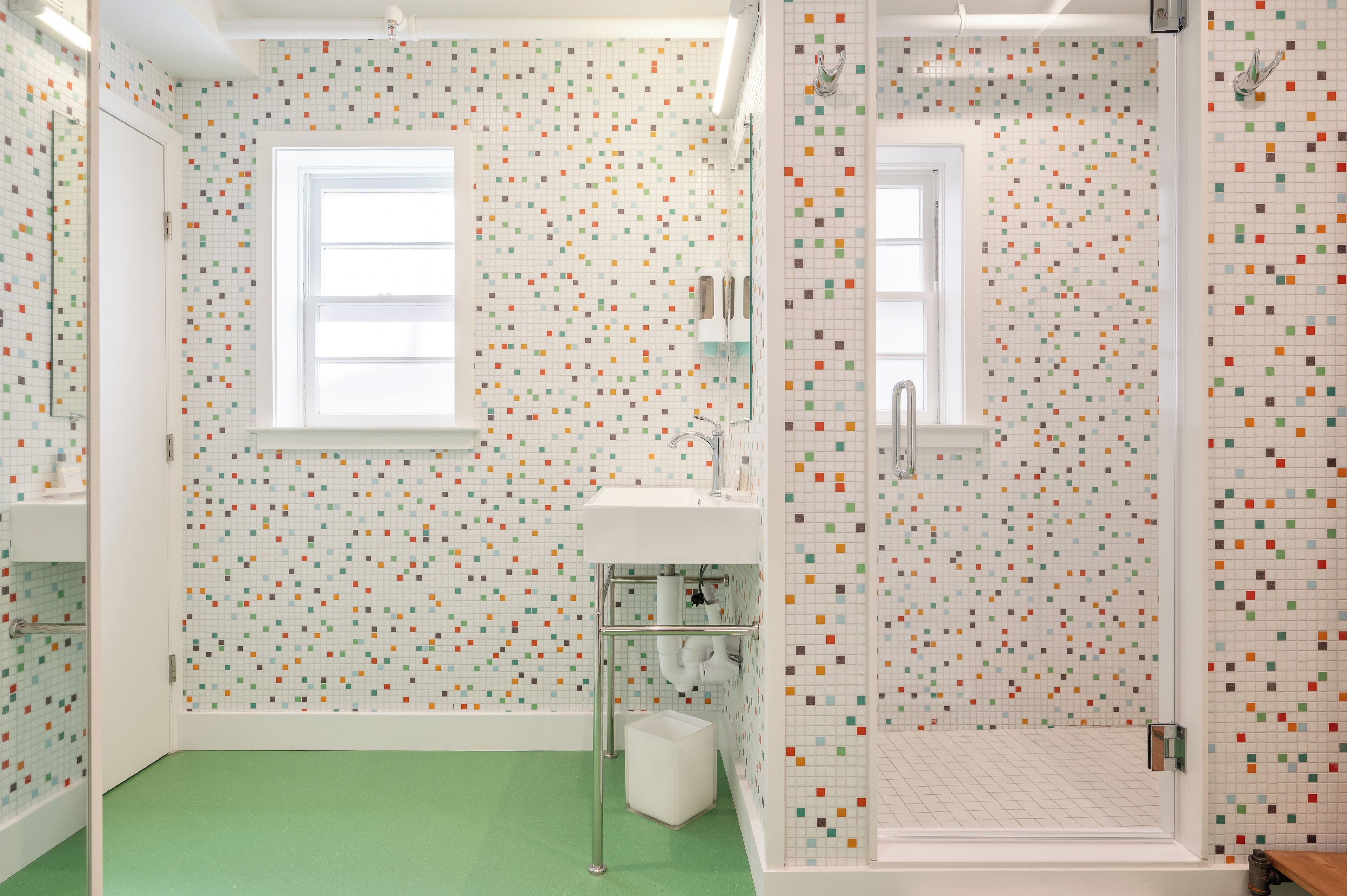 Un baño con piso verde, lavamanos blanco y zona de ducha.