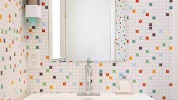 A bathroom with a white sink, a mirror, and colorful mosaic tiles on the walls.