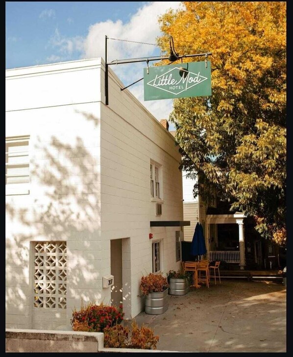 A white building with a sign for 'Little Mod Hotel' and a patio area with outdoor seating.