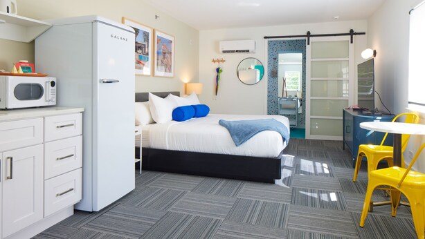 Ein Hotelzimmer mit Bett, Mikrowelle, Schreibtisch, Stuhl und einem kleinen Tisch.