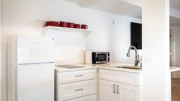A modern kitchen with white cabinets, a white refrigerator, a microwave, and a sink.