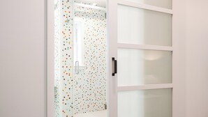 Ein Zimmer mit einer Schiebetür zu einem Badezimmer mit farbenfroher Fliesenwand.