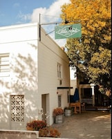 A white building with a sign for 'Little Mod Hotel' and a patio area with outdoor seating.