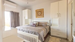 A bedroom with a bed, a wardrobe, a radiator, and a window with curtains.