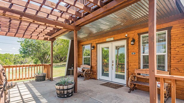 Une cabane en bois dotée d’un porche couvert, de grandes fenêtres et d’une porte d’entrée.