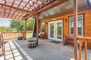 A wooden cabin with a covered porch, large windows, and a front door.