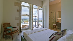 A bedroom with a large bed, a chair with a cushion, a bathroom with a shower, and a balcony with a view. - Villa OLEANDRA: Luxe, daily service, sea & sunset impressive views, 24mt pool (Isola)