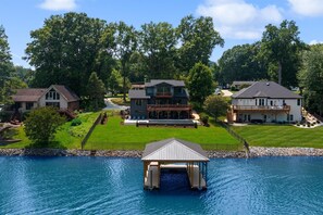 A large house with a dock over a lake, surrounded by lush greenery and other houses. - Elysian Shores W/heated Pool & Optional Boat Rental (Mooresville)