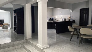 Una cocina moderna con armarios oscuros, una isla central y una zona de comedor con sillas.