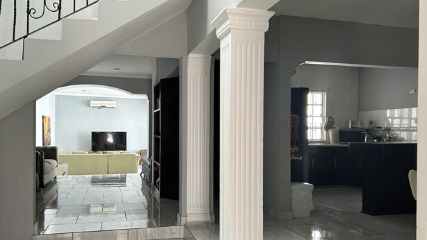 Amplia sala de estar con televisor, sofá y zona de cocina con lavaplatos y microondas.