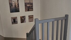 En trappa med ett träräcke och en vägg med fyra inramade tavlor som föreställer stadsmotiv.