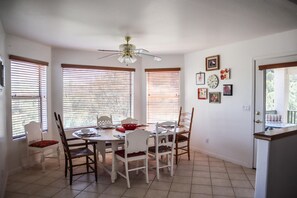A dining area with a round table, white chairs, and a ceiling fan.