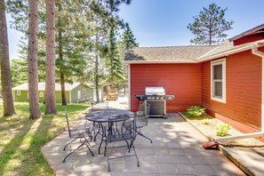 A patio with a grill, outdoor seating, and a red building. - Waterfront Pequot Lakes Cabin: Fire Pit + Views! (Pequot Lakes)