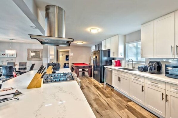 Kitchen features a gas stove, stainless steel appliances, and a central island.