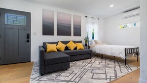 A modern bedroom with a grey sofa, a bed, and a geometric rug. - Modern Studio in Los Angeles (Los Angeles)
