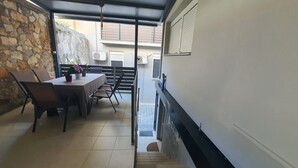 A dining area with a table and chairs, a potted plant, and a stone wall. - Black suites 1 (Chania)