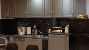 A modern kitchen with grey cabinets, a microwave, a toaster, and a refrigerator. - Black suites 1 (Chania)