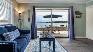 Un soggiorno con vista su un lago, una ventola a soffitto e un tavolino con una rivista.