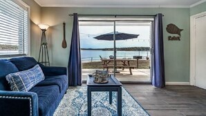 A living room with a view of a lake, a ceiling fan, and a table with a magazine. - #6 The Point - Double Bed Room (Hot Springs)