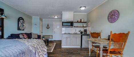A compact living space with a bed, a dining table, and a kitchenette.