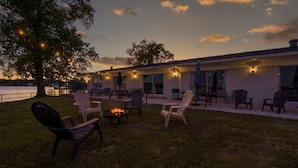 An outdoor seating area with chairs and a fire pit, overlooking a body of water. - #10 Main Channel - King Room (Hot Springs)