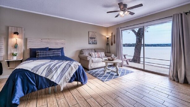 A bedroom with a large bed, a ceiling fan, a sofa, and a view of the water. - #15 The Cove - Double Bed Room (pet-friendly) (Hot Springs)