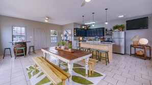 A spacious kitchen with a dining area, a ceiling fan, and a TV mounted on the wall. - #15 The Cove - Double Bed Room (pet-friendly) (Hot Springs)