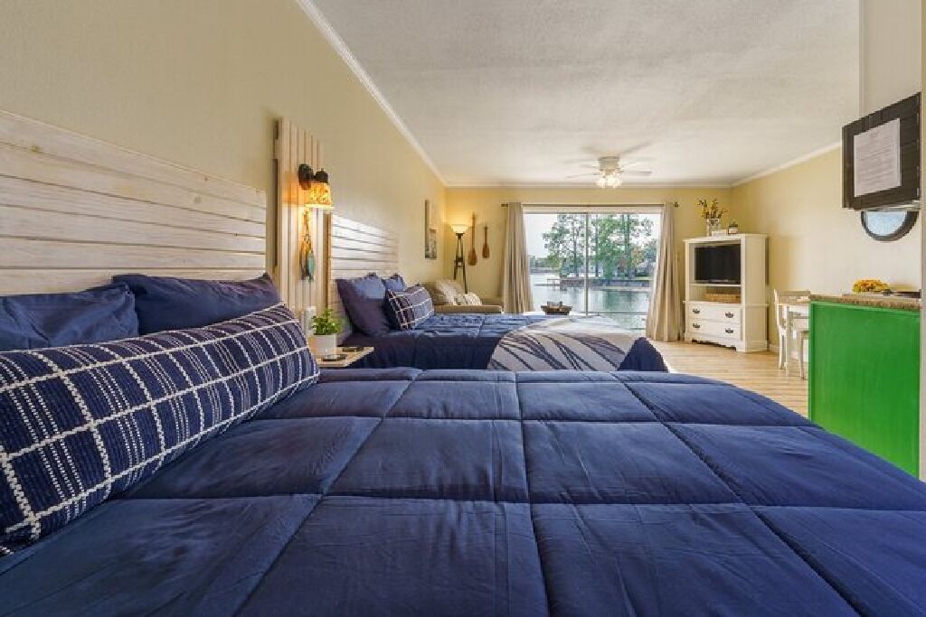 A bedroom with two beds, a desk, and a view of a pool.
