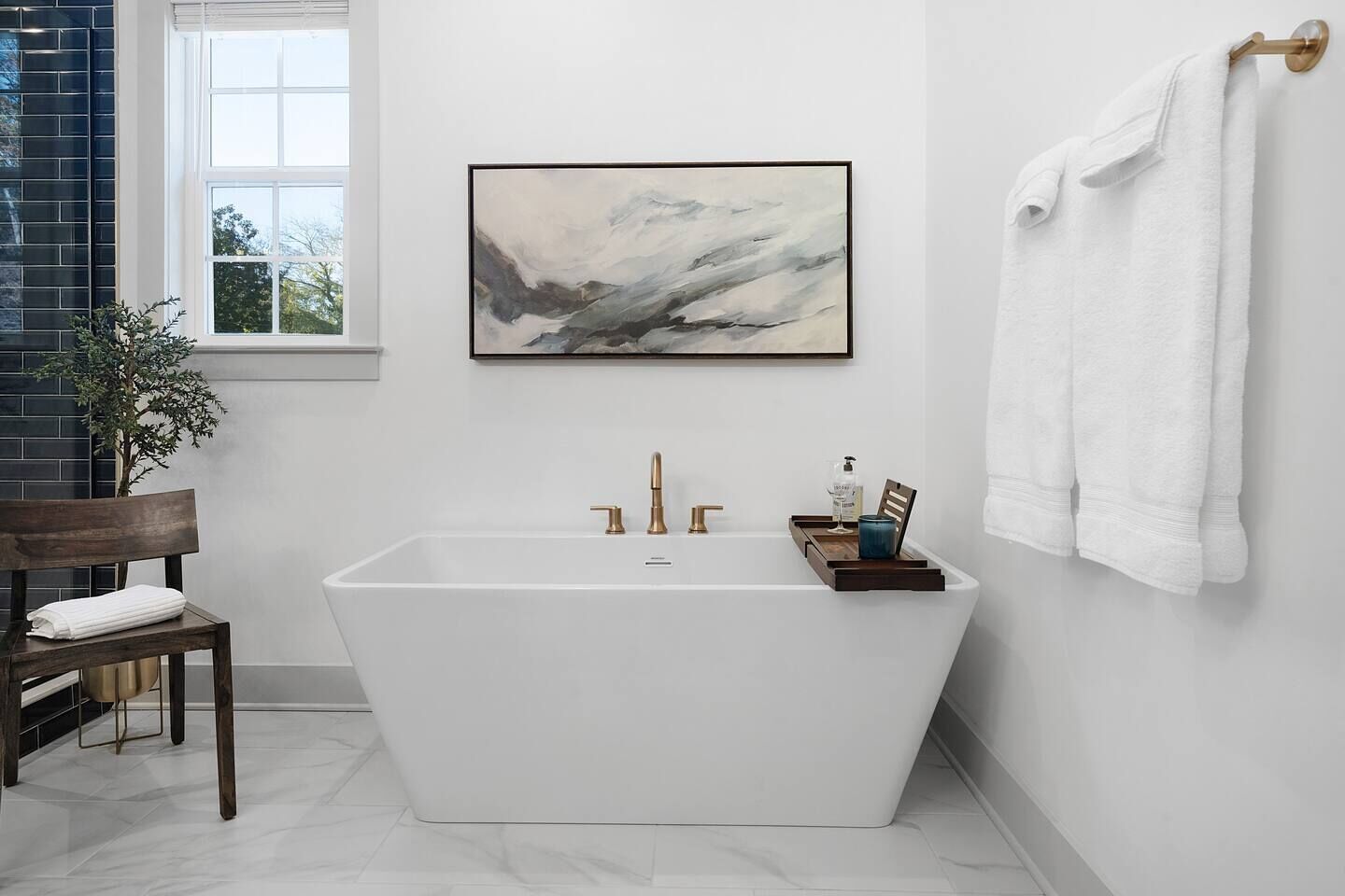 A modern bathroom with a freestanding bathtub, a framed abstract painting, and a towel rack.