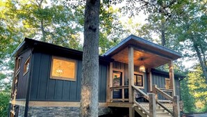 A cabin with a stone foundation, wooden exterior, and a staircase leading to a porch.