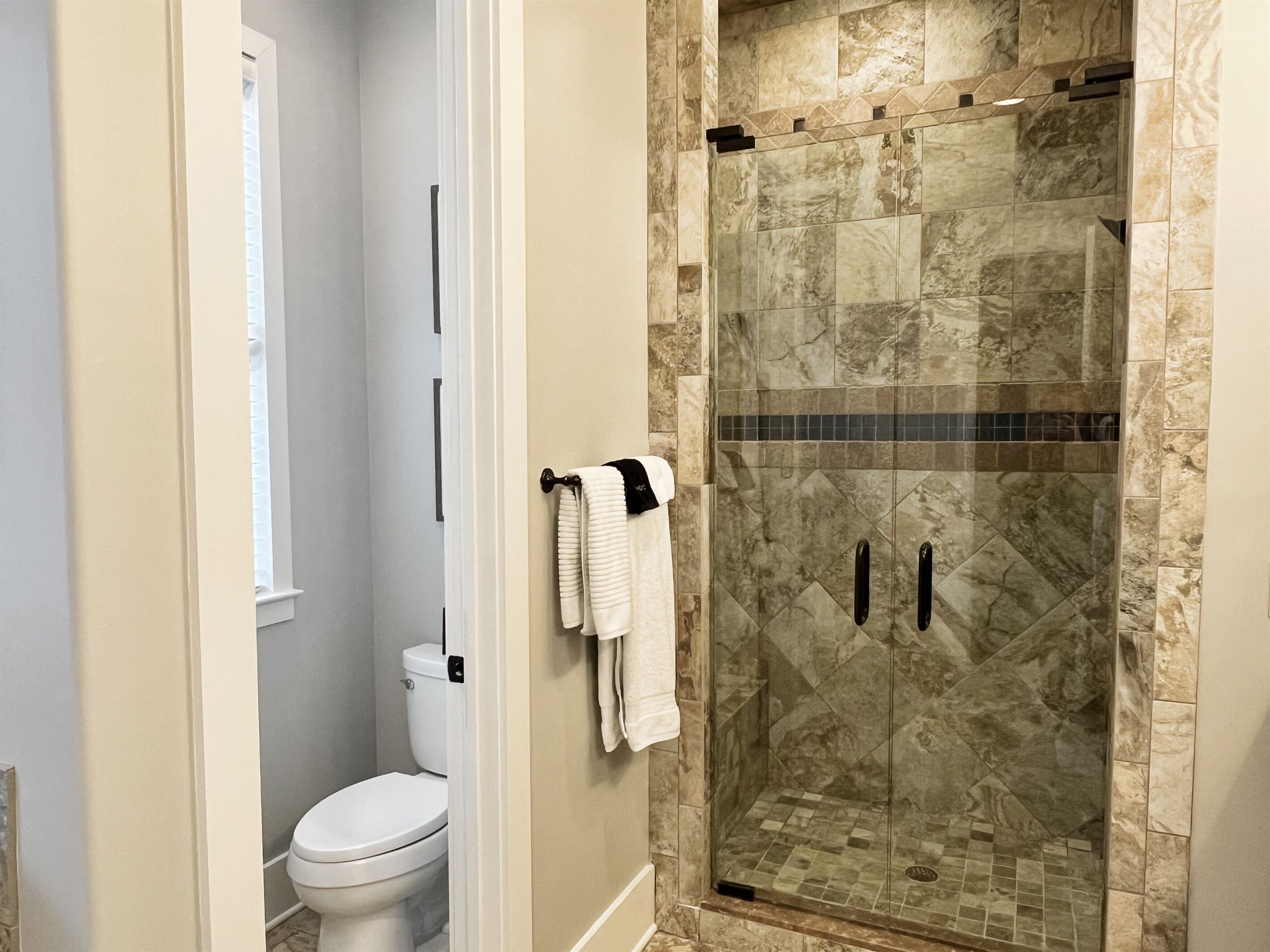 Une salle de bain avec une douche à parois de verre, des toilettes et un porte-serviettes.
