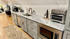 A modern kitchen with a marble countertop, stainless steel appliances, and a patterned rug. - Lofty Dream | Stylish Northshore Loft Stay (Chattanooga)