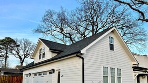 A two-story house with a garage, a sloped roof, and a tree in the background. - Lofty Dream | Stylish Northshore Loft Stay (Chattanooga)