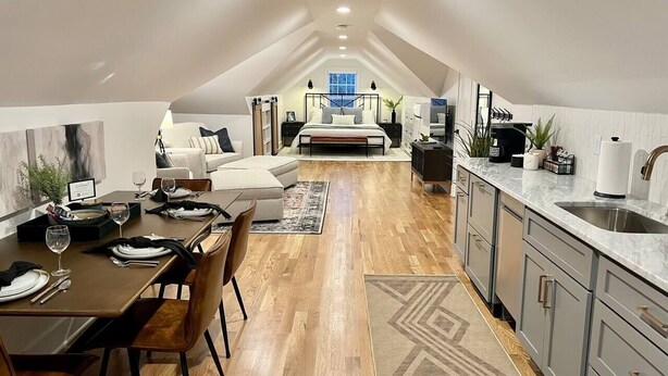 A modern loft-style bedroom with a large bed, a desk, and a dining area. - Lofty Dream | Stylish Northshore Loft Stay (Chattanooga)