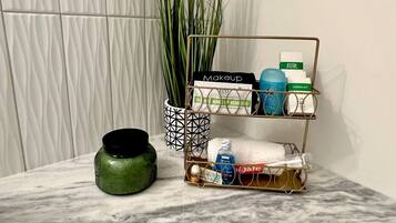A marble countertop with a makeup organizer, a green vase, and a tall plant.