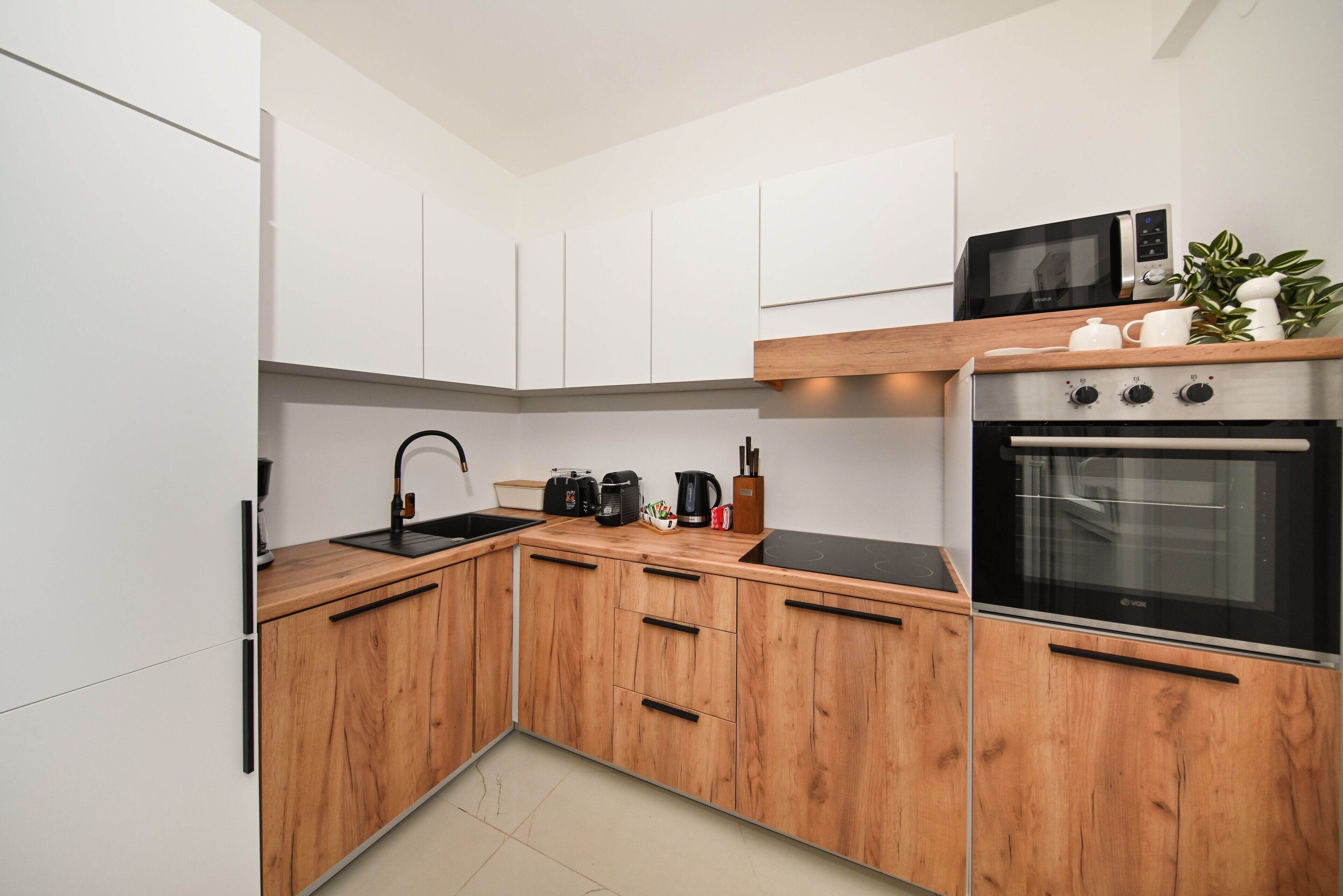 Una cocina moderna con armarios de madera, un microondas negro y un horno.