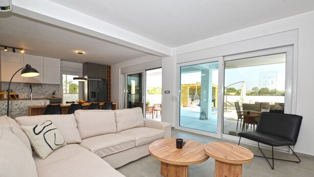 A modern living room with a sofa, two wooden coffee tables, and a black chair. - Villa 5H (Kanfanar)