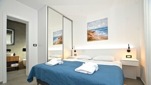 A bedroom with a large bed, two bedside tables, a nightstand, a mirror, and artwork on the wall. - Villa 5H (Kanfanar)
