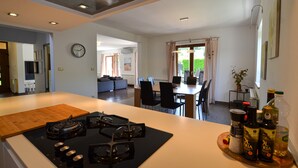 A modern kitchen with a gas stove, a dining area with a table and chairs, and a living room with a sofa. - Villa dado (Kanfanar)