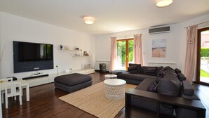 A modern living room with a flat-screen TV, a sofa, a coffee table, and a large window with curtains. - Villa dado (Kanfanar)